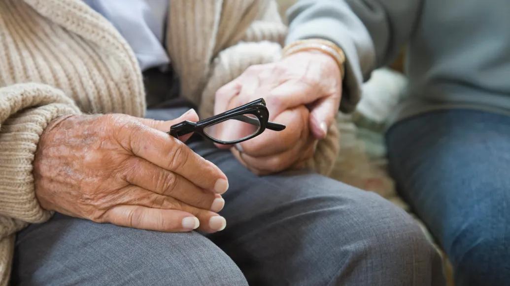 older woman holding glasses in lap