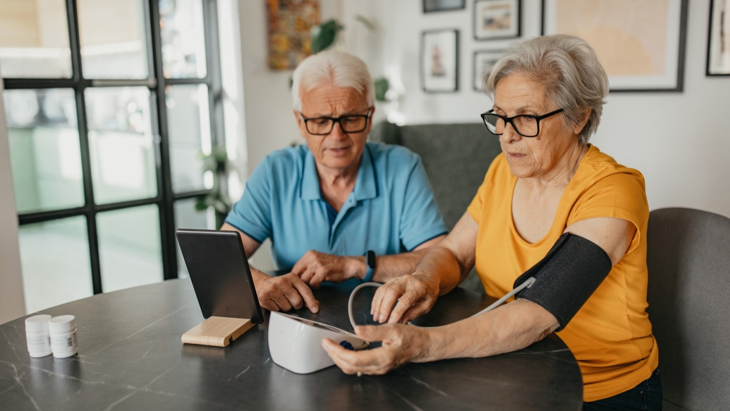 two older people taking blood pressure over breakfast