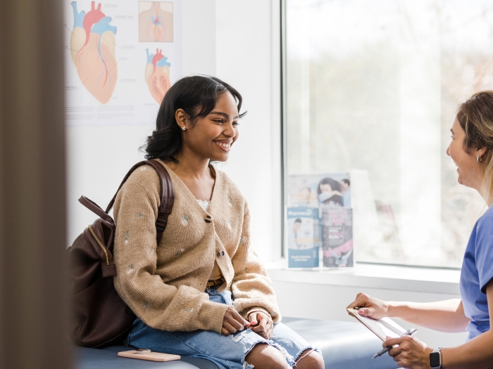 a patient with a medical professional in scrubs in an exam room talking