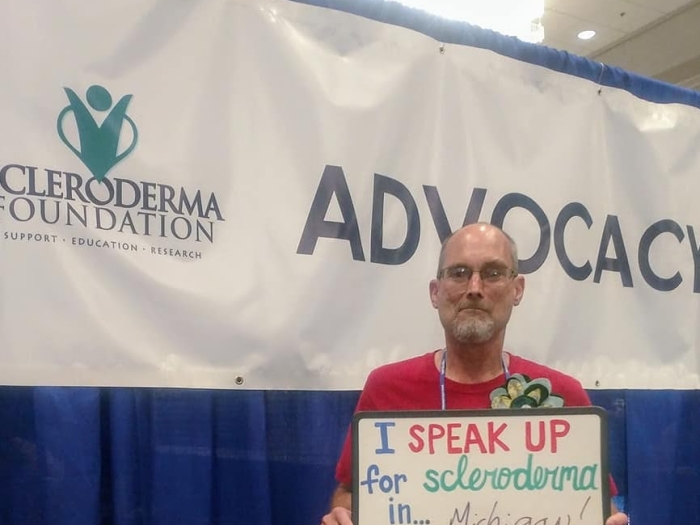 Michael holding a sign that says "I speak for scleroderma in Michigan"