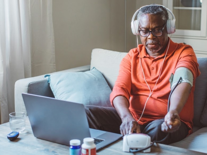 Senior man with headphones in front of a laptop with cuff