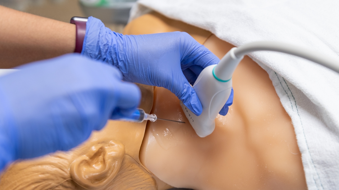 up close view of needle and hands holding ultrasound wand 
