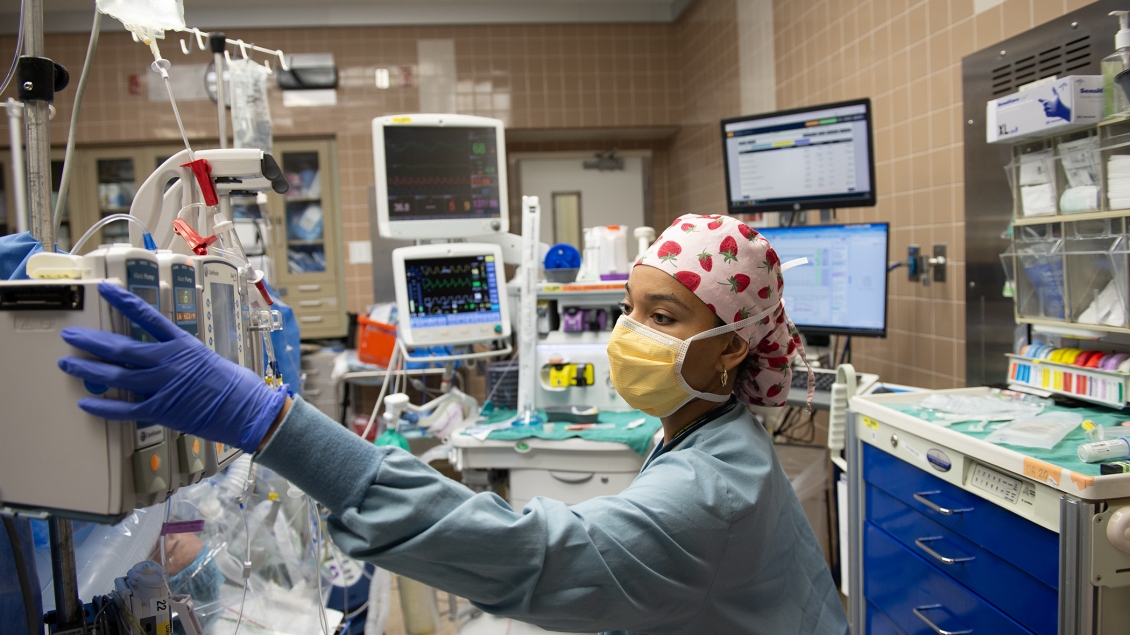 Nurse reaches over to check levels of the drip bags 