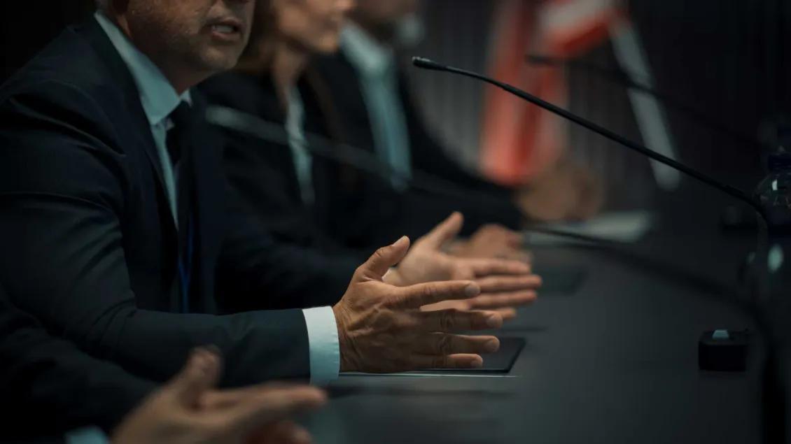 Business people speaking into microphones at a table
