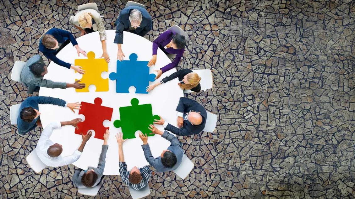Adults Working Puzzle Around Table