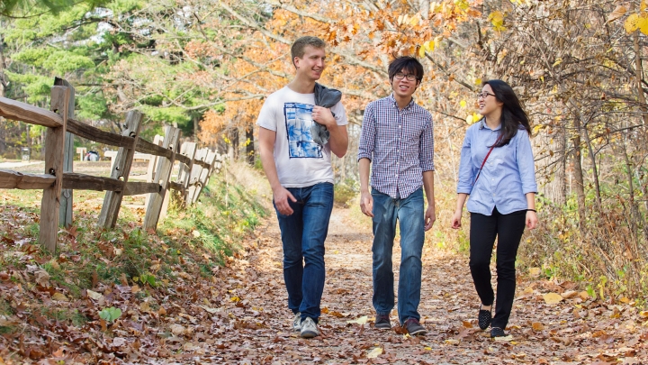 Three people walking outside on a nature trail