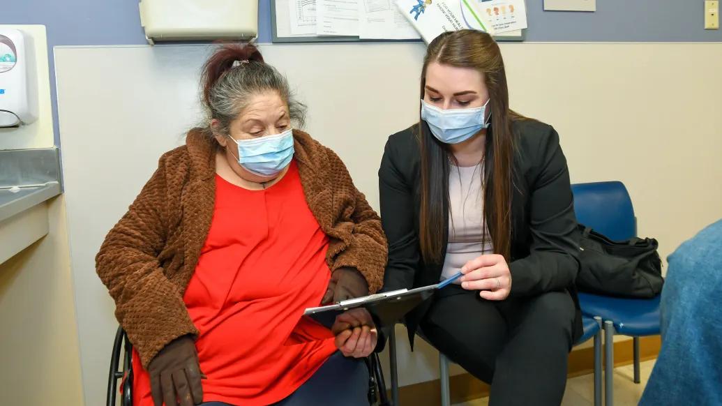 woman sitting looking at paperwork wearing blue masks