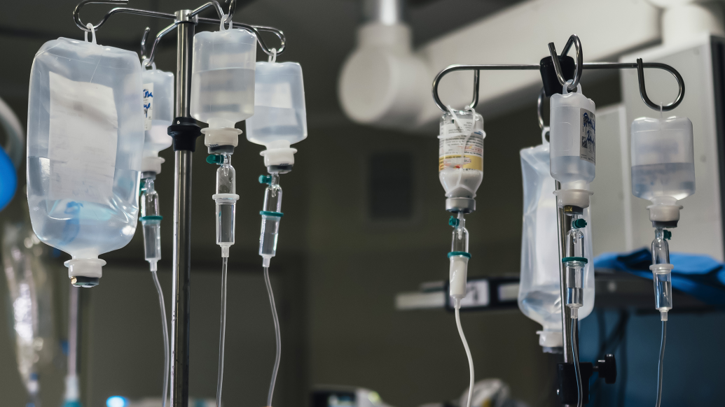 Close-up of multiple IV fluid bags in an operating room