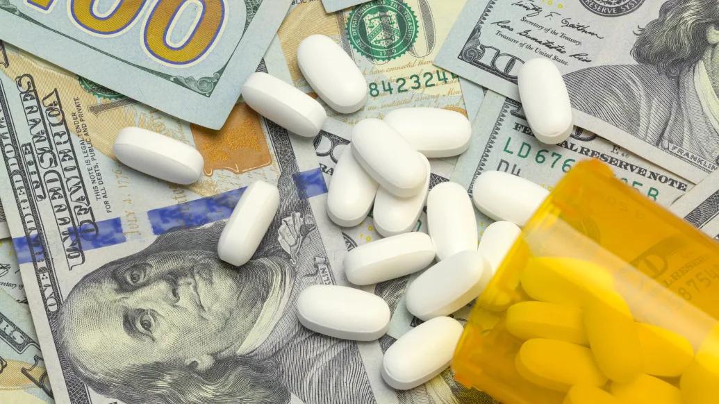 prescription pills spilling out of a bottle on a pile of money