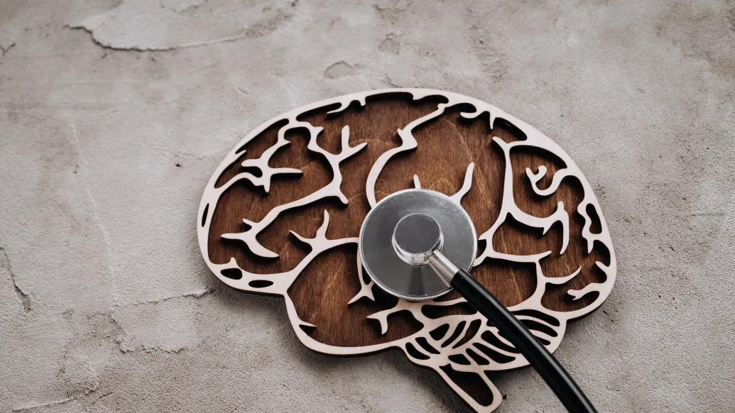 Wood carving of a brain with a stethescope on top