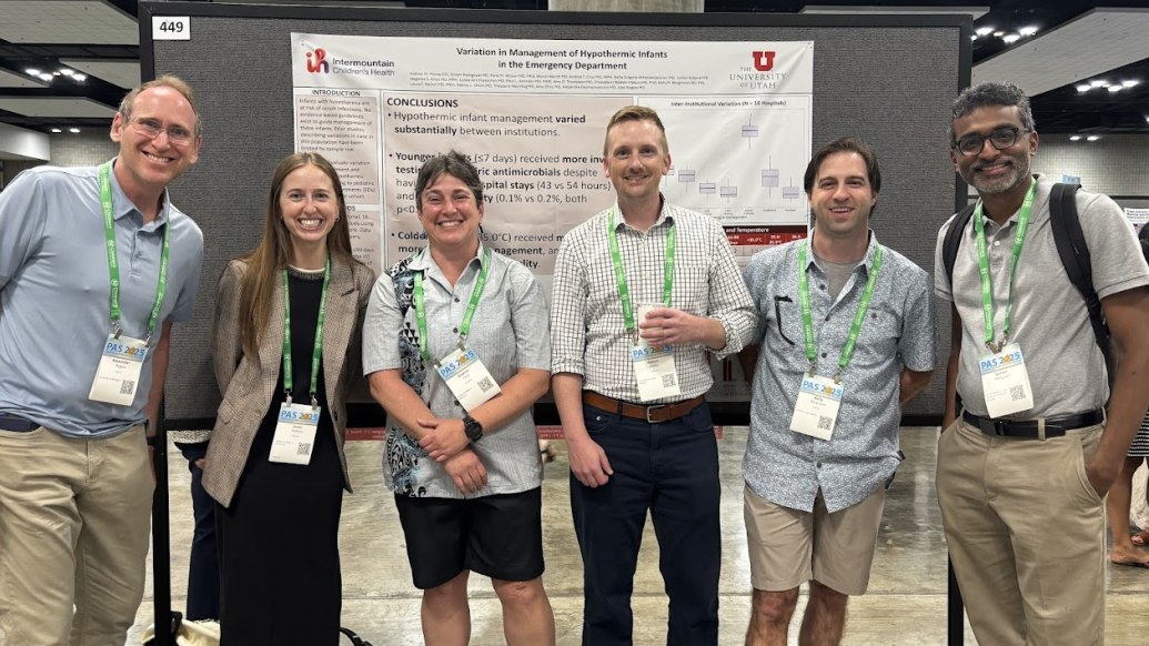 PAS attendees pose in front of a poster