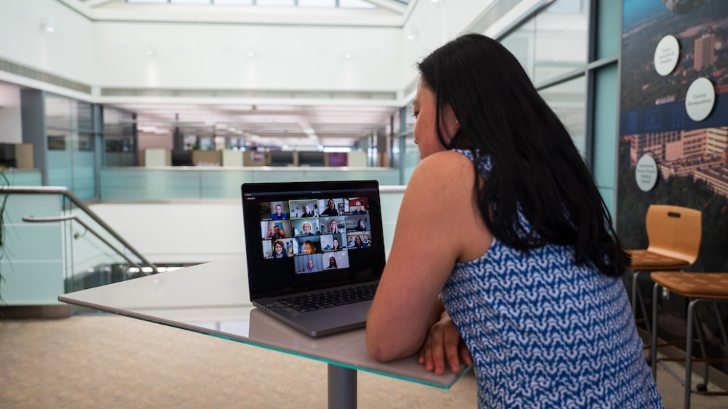 Photo of woman sitting in front of a laptop looking at a Zoom meeting 