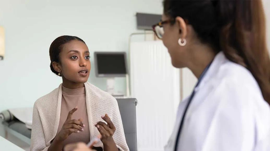 Black woman talks to her female doctor in an exam room
