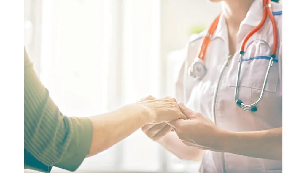 A healthcare professional holds the hand of a patient