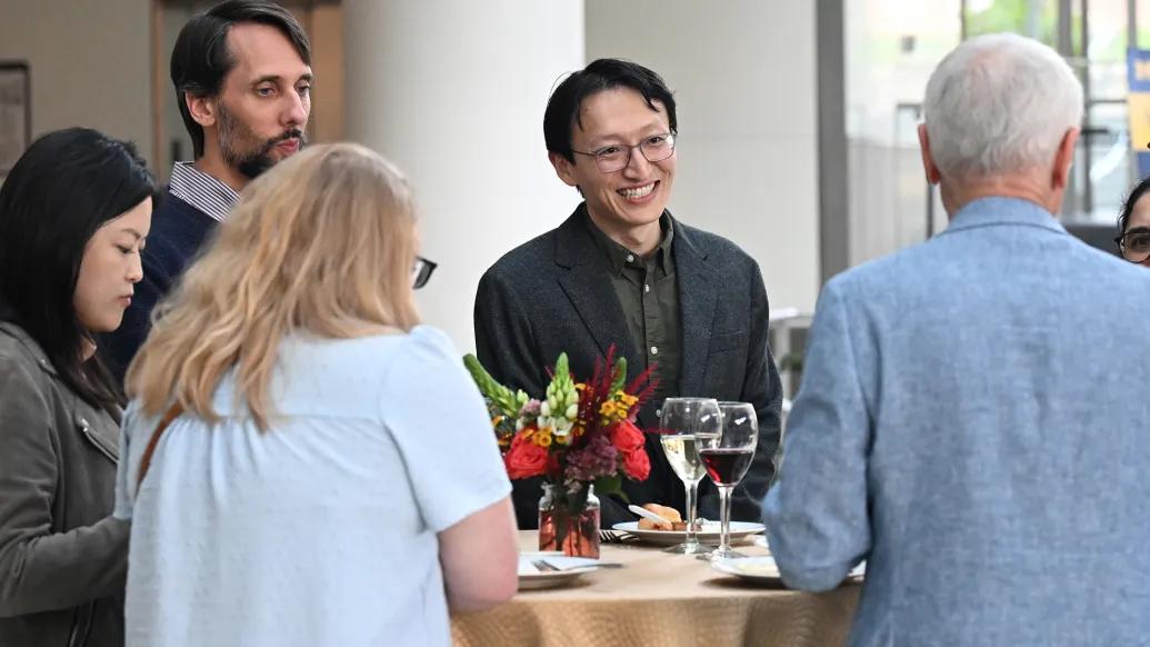 Yunlu Zhu smiles at a table with colleagues