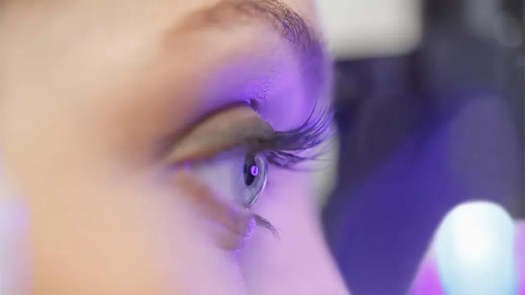 Eye and eyebrow with purple light shining on it