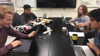 a group of students with laptops discussing in a class room