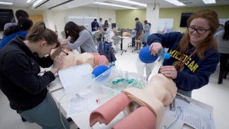 Students actively participating in a hands-on simulation lab, practicing medical procedures using lifelike mannequins.