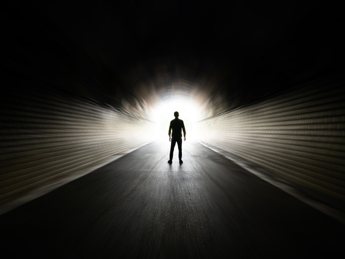 black room with person visual far away walking towards glowing light