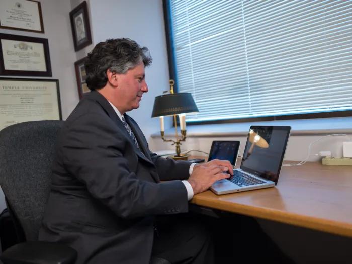 faculty member typing on computer inside office