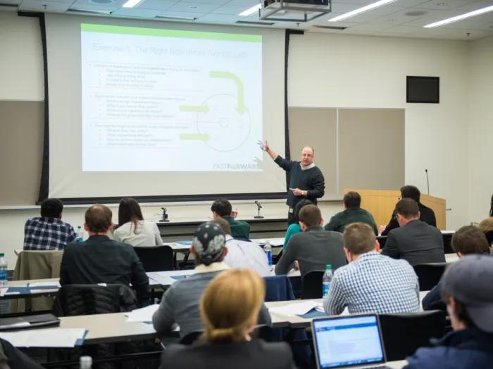 instructor pointing at screen in classroom with students