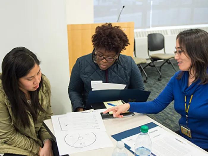 three people discussing papers in a group project