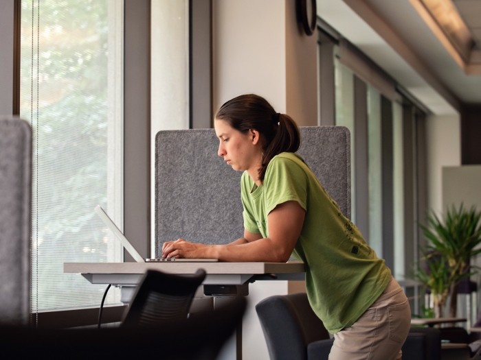 woman standing in the lounge area working on a computer in the taubman health sciences library 