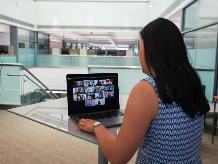 Photo of a woman standing in front of a computer with Zoom