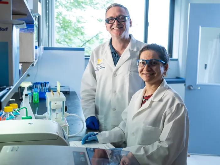 woman and man looking at camera and smiling while in a lab