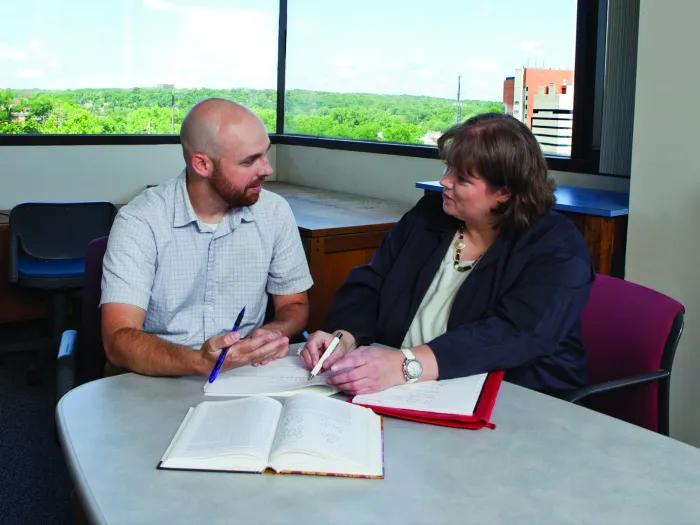 man and woman discussing notes in office