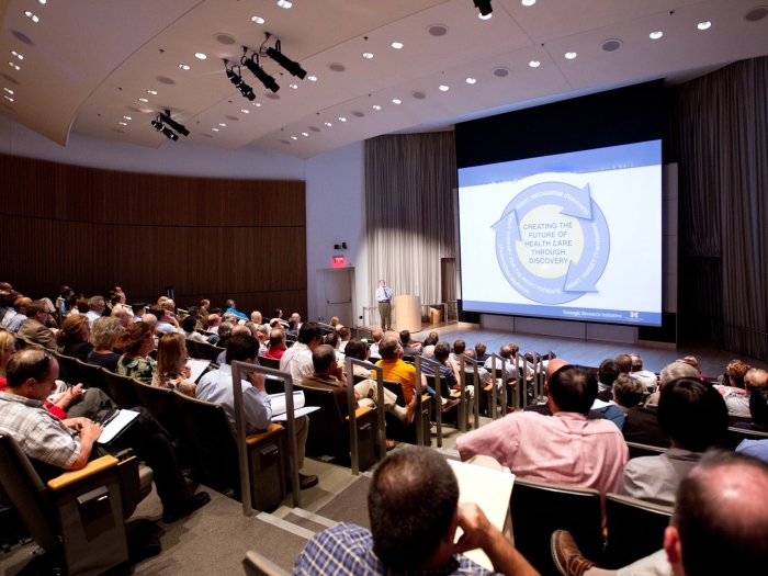 A speaker and attendees at an event in Kahn Auditorium at BSRB