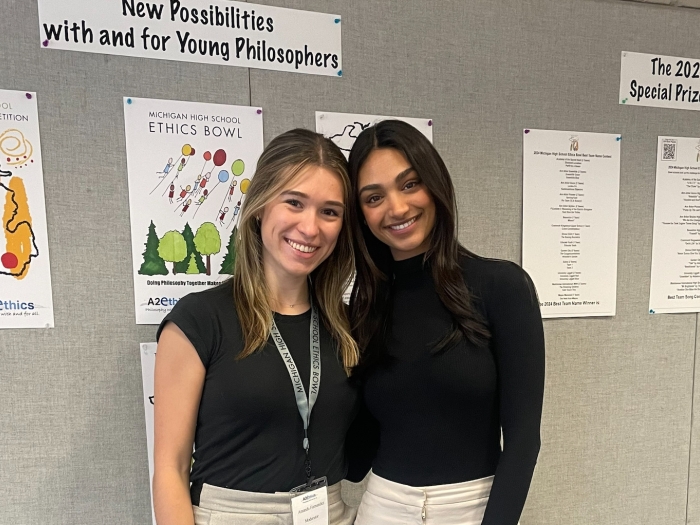 Two medical students standing in front of a bulletin board smiling at camera