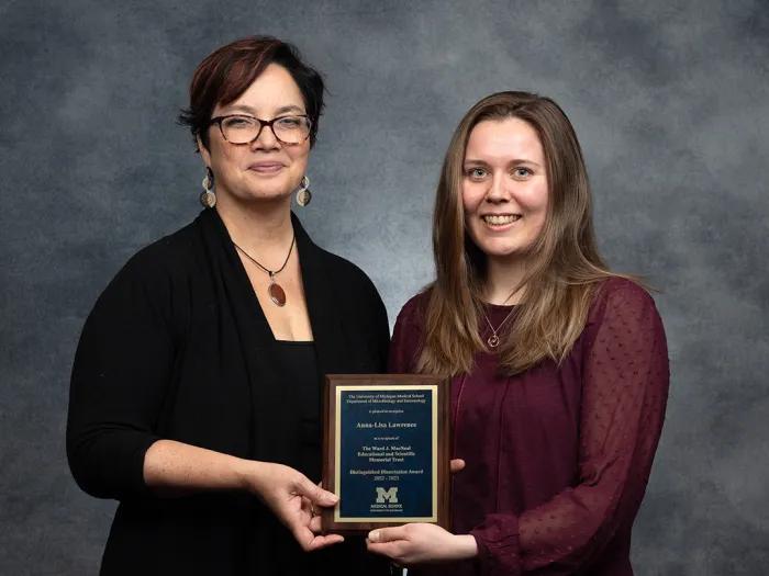 Professor Mary O'Riordan (left) and Dr. Anna-Lisa Lawrence hold the MacNeal Award plaque