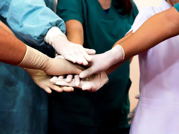 Five gloved hands of a medical team together in a circle