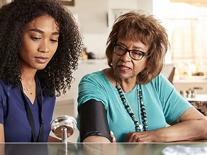 Healthcare professional reviews older woman's blood pressure