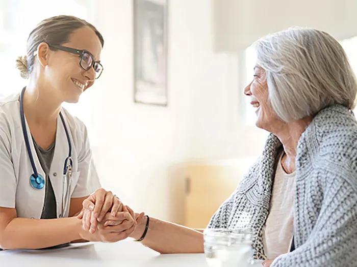 Doctor smiling at the patient holding hands.