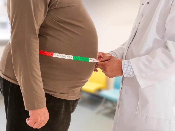 doctor measuring an obese man's waist
