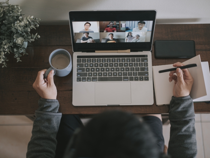 An overhead view of a person sitting at a laptop, participating in a Zoom meeting.