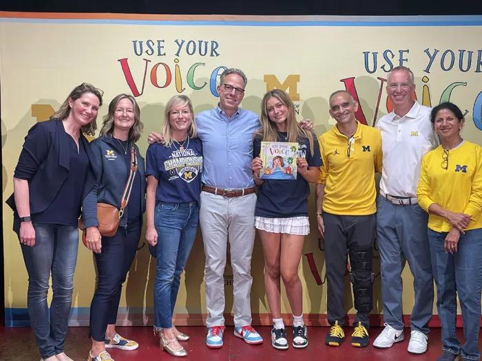 Smiling photo of eight people standing in front of a backdrop that says, "Use Your Voice".