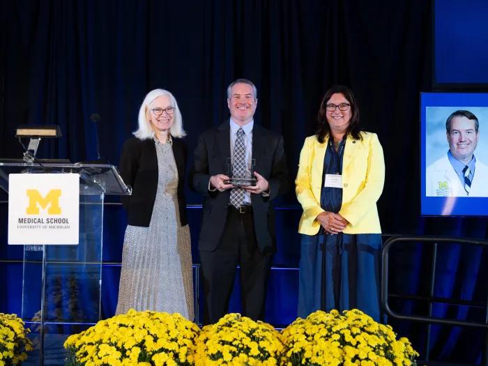 Dr. Brian Callaghan with his UMMS Early Distinguished Career Award, flanked by Debra Weinstein, MD and Samantha Spencer, MD