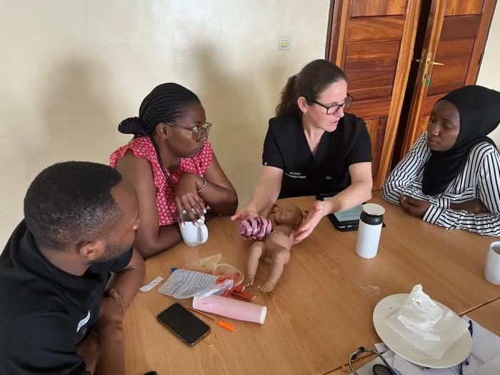 Female doctor teaches local Rwandan doctors with an infant practice model.