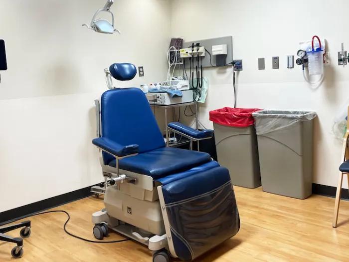 A treatment room featuring a dental chair, an overhead light and dental tools