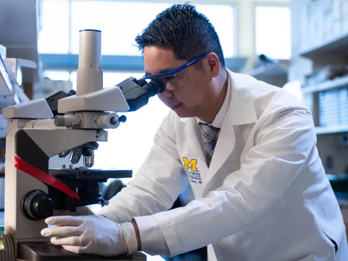 Dr. Kevin Chen looking through a microscope in the lab