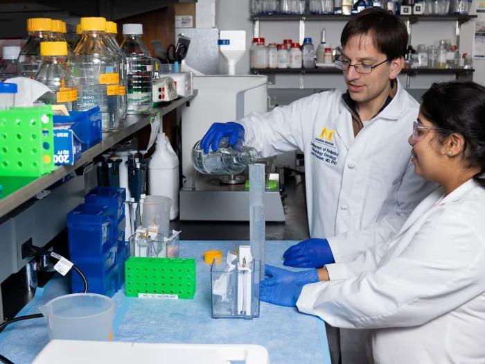 Dr. Presner and lab member measuring a solution in the lab