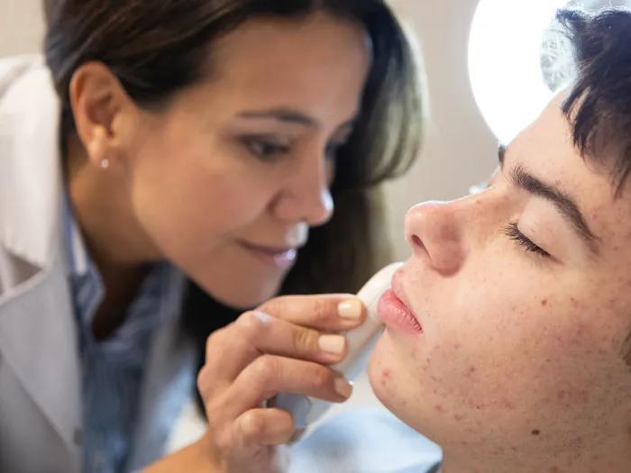 doctor looking close up at patients skin with microscope-like tool
