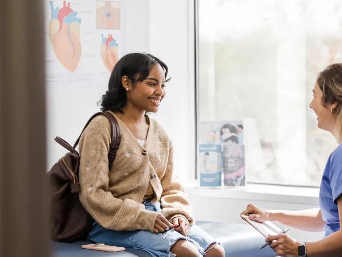 a patient with a medical professional in scrubs in an exam room talking