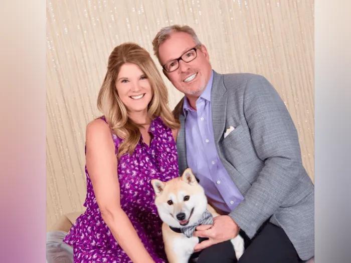 Smiling seated portrait of Glenn and Trish Granger. They are both holding their dog, Max.