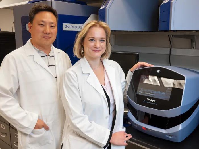 two researchers standing in lab with device