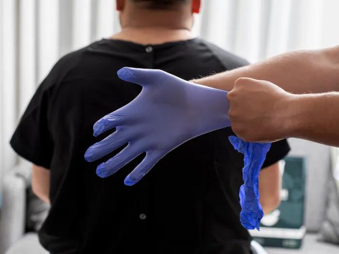 medical glove purple behind patients back being put on