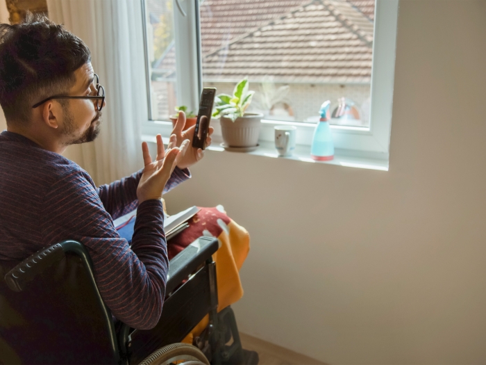 man in wheelchair at home with phone talking on facetime